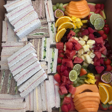 Load image into Gallery viewer, Box containing assorted sandwiches and a fruit platter.